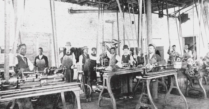 Historic photo of Lincoln students learning industrial trades inside Industrial Hall in the late 1800s, showing hands-on vocational training in a classroom/workshop setting.