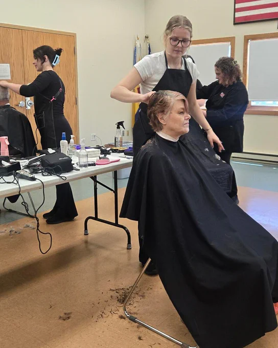 A cosmetology student styles a community member’s hair during the free haircut event.