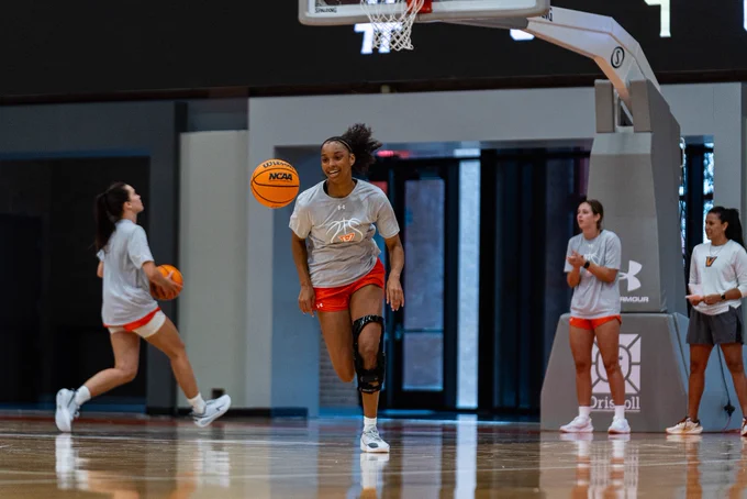 Player runs through a drill during summer practice while teammates and coaches observe.