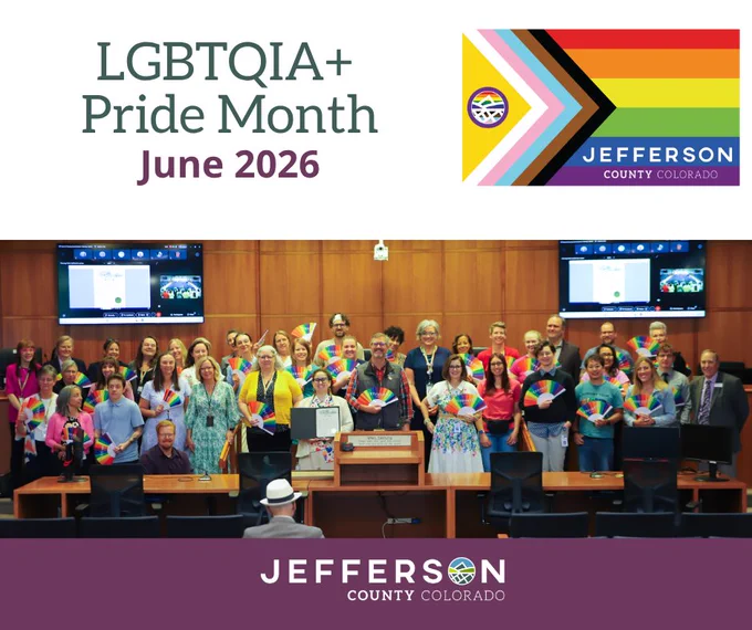 A group of people in a conference room pose for a photo, holding colorful items. The image text reads "LGBTQIA  Pride Month June 2026." 