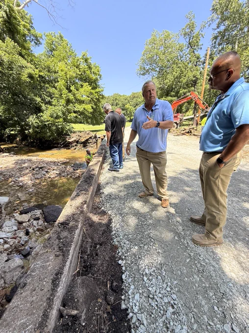 photo shows OEM staff talking to an Ottawa County official and reviewing flood damage to a roadway.