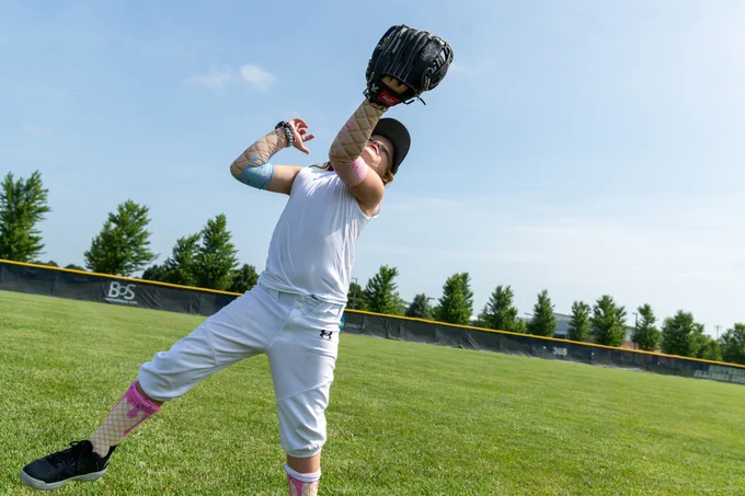 Camper reaches overhead to catch a fly ball during a drill at the UIS Baseball youth camp.