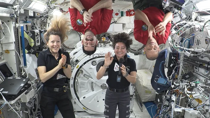 Expedition 74 crew members (from left) Sophie Adenot, Jack Hathaway, Jessica Meir, and Chris Williams smile, wave, and congratulate the Artemis III crew in a recorded video message.