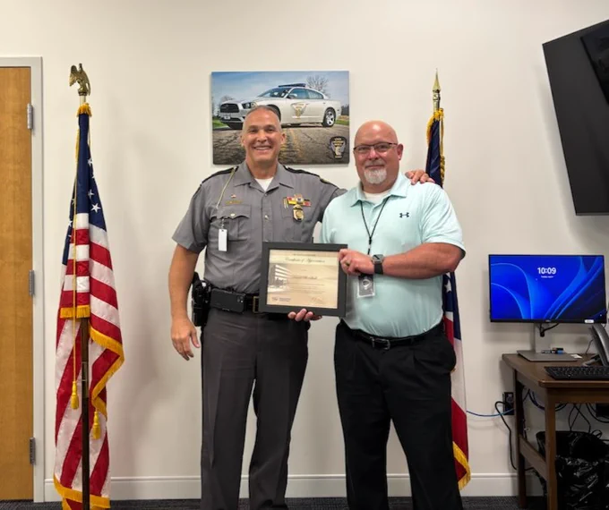 Lieutenant Colonel Swindell and IS2 Hall stand with a framed certificate for 35 years of service. 