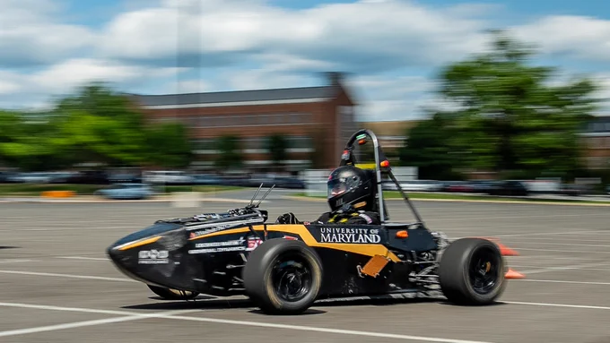 A person driving a racecar through a parking lot with a blurred background