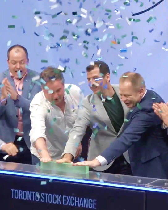 Abe Dyck and speakers at the CCIC ring the closing bell at the TSX. Confetti is seen falling from the ceiling as they push the green bar to close the market.