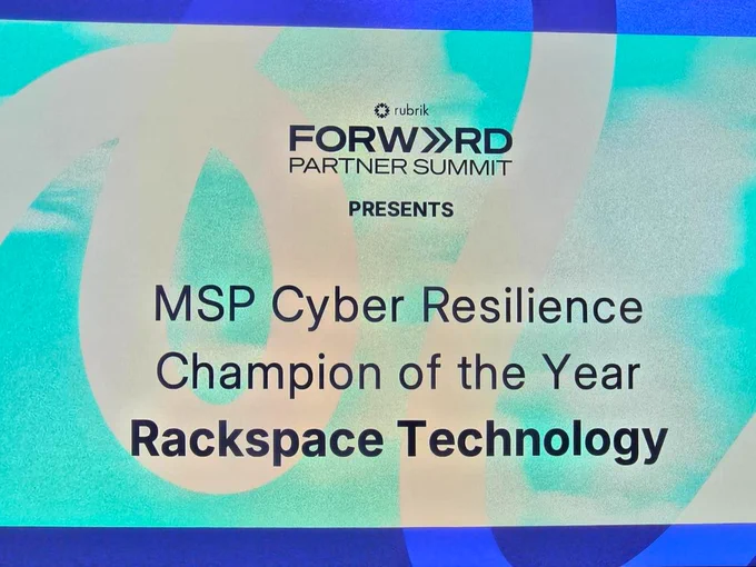Event slide with the text: "rubrik FORWARD PARTNER SUMMIT PRESENTS MSP Cyber Resilience Champion of the Year Rackspace Technology." The background features abstract blue and green shapes.