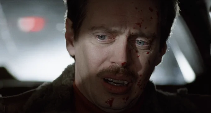 closeup on Steve Buscemi with a little bit of blood splatter on his face, mouth slightly open, his eyes and right cheek illuminated by a stripe of light, the rest of him in shadow 