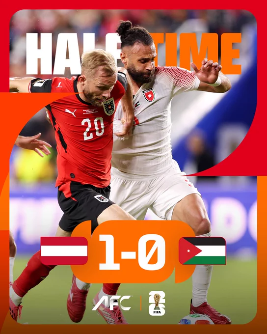 An intense soccer match at halftime with one team leading 1-0. Players from both teams are physically competing for the ball.