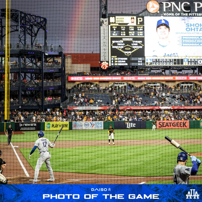A photo of Shohei Ohtani up to bat with a rainbow in the sky behind left field.