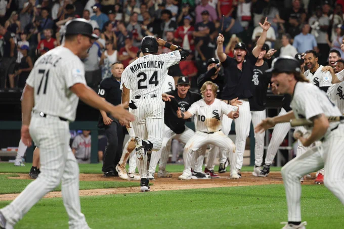 White Sox players surround home plate to congratulate Braden Montgomery after he hit a walk-off home run in his MLB debut on Tuesday night. They are wearing a mixture of white pinstriped Chicago White Sox jerseys and black training shirts.