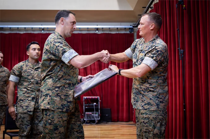 A senior Marine presents an award to a band leader during a ceremony recognizing excellence in military music.