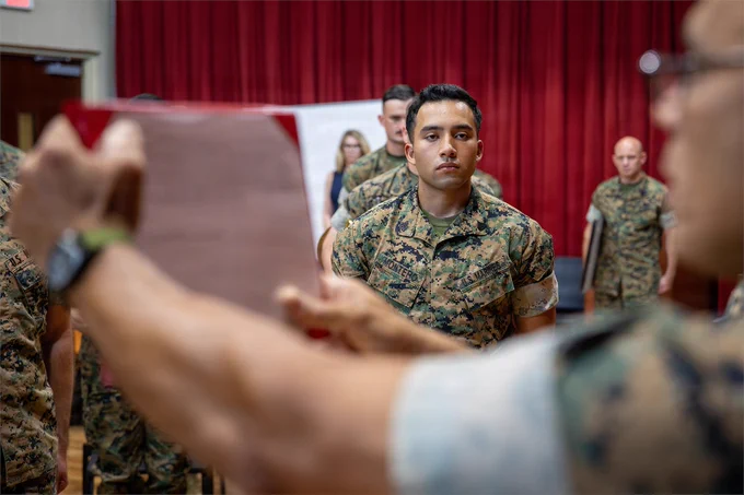 A Marine stands at attention while an award citation is read during a recognition ceremony with the Marine Forces Reserve Band.