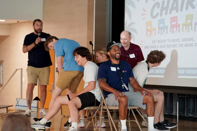 Community Education staff rush to sit in chairs in a friendly game of Musical Chairs at a Summer Kickoff event
