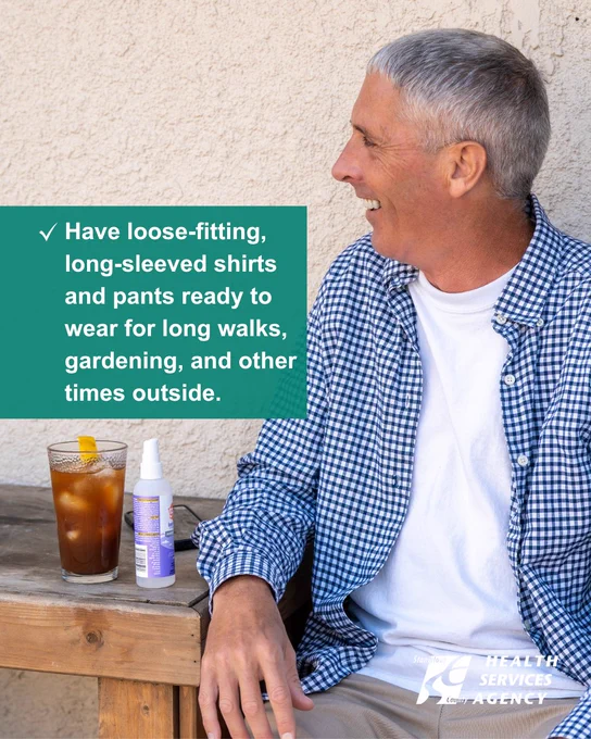 A man sits on an afternoon porch with insect repellent on the table, ready for outdoor activities in loose-fitting clothing.