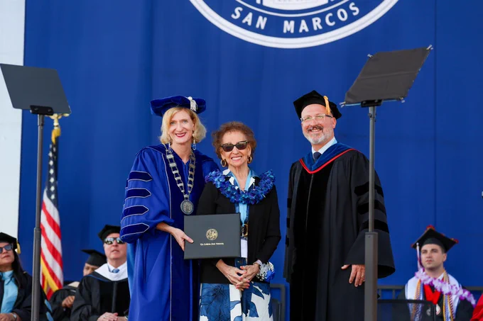 Theresa Rios, wife of Dan Rios, is presented with Dan's honorary degree at the CHABSS graduation ceremony on May 15, 2026. From left: CSUSM President Dr. Ellen Neufeldt, Theresa Rios, and CSUSM Provost, Dr. Carl Kemnitz.