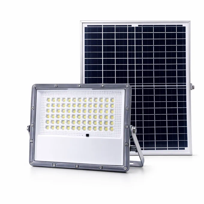 Kit de iluminación solar sobre un fondo blanco. En primer plano se muestra un reflector LED rectangular de carcasa gris con un soporte metálico ajustable y múltiples diodos LED amarillos visibles en su interior. Justo detrás, se encuentra su panel solar fotovoltaico rectangular con marco de aluminio plateado y celdas oscuras.
