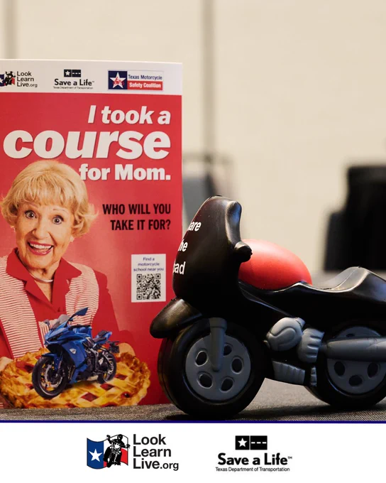 A promotional display featuring a flyer with "I took a course for Mom. Who will you take it for?" alongside a toy motorcycle. Logos for "Look Learn Live.org" and "Texas Department of Transportation" are visible.
