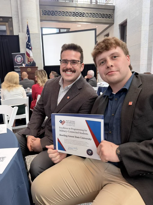 Two students holding up a military student award