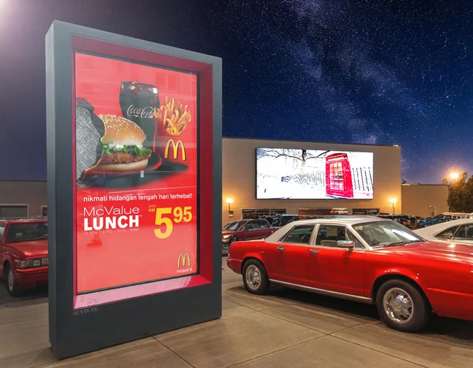 Outdoor LCD advertising display shown at night in a street-side or retail environment.