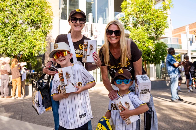 Photo of a family of Padres fans holding their "Bogey Goes Boom" bobblehead giveaway. They are smiling for the camera. They are wearing the different Padres shirts and jerseys.