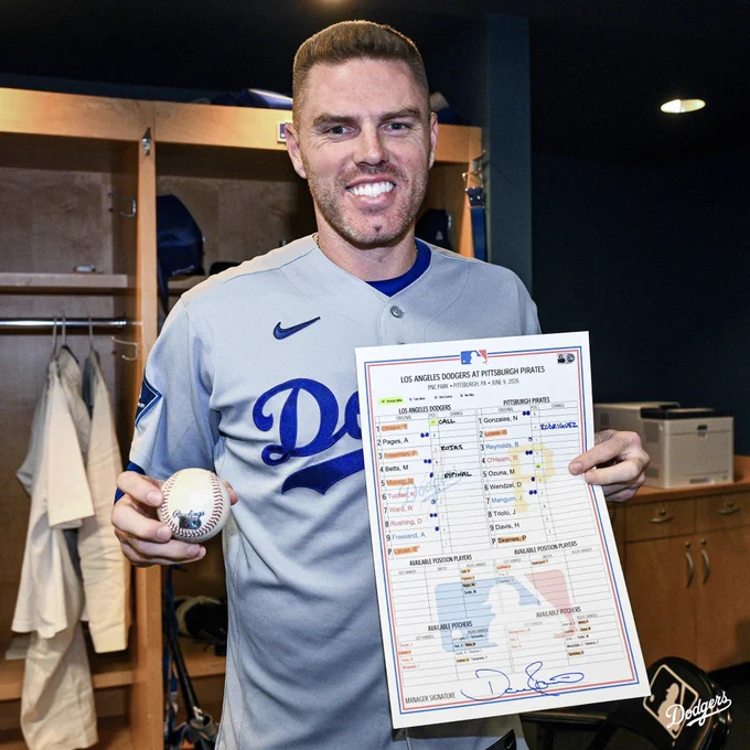 A photo of Freddie Freeman holding up his 2,500th career hit baseball and lineup card.