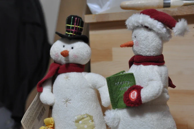 A snowman couple, Felicia and Frank, positioned in a medium shot sitting on wooden stairs. ✅