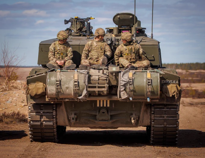 Three personnel on the back of a Challenger 2 battle tank.