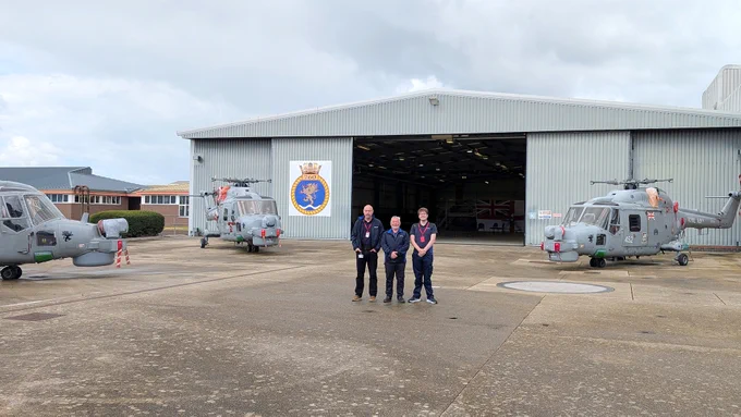 A photo of three male STS Defence employees outside the 760 naval air squadron hangar at HMS Sultan.