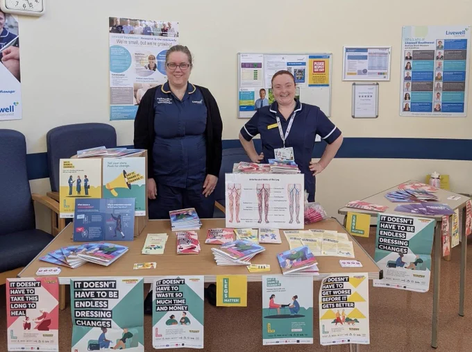 2 nurses stood behind a stand full of posters and leaflets