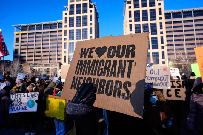 Protester holds sign reading "We our immigrant neighbors" at protest gathering