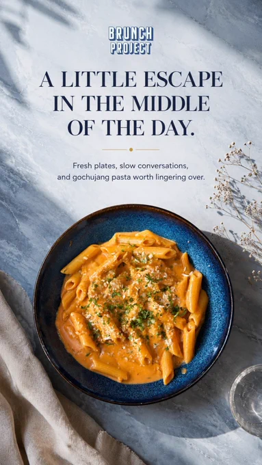 A beautifully plated serving of Gochujang Pasta at The Brunch Project in Koramangala, Bangalore. The dish features perfectly cooked penne pasta coated in a rich, creamy Korean-inspired gochujang sauce, topped with freshly grated parmesan cheese and finely chopped herbs. Served in a deep blue ceramic bowl, the vibrant orange sauce contrasts elegantly against a soft marble-textured background. Natural light casts gentle shadows across the table, creating a calm and inviting brunch atmosphere. The image includes the text “A Little Escape in the Middle of the Day” highlighting the relaxed café experience and slow dining culture of The Brunch Project. This signature pasta combines creamy comfort with a subtle spicy kick, making it a favourite among pasta lovers, brunch enthusiasts, and diners seeking unique flavours in Bangalore. Perfect for lunch meetings, casual catch-ups, work breaks, and all-day brunch occasions in Koramangala.