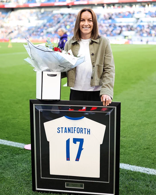 Lucy Staniforth holding flowers and framed Lionesses shirt. 

