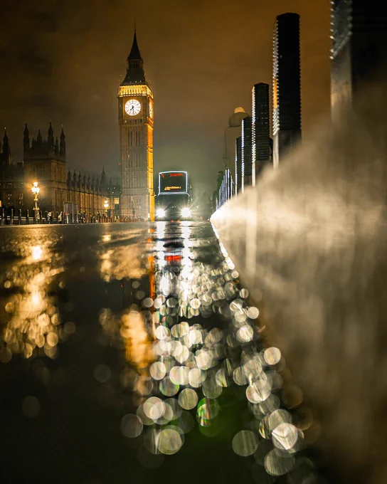 A moody shot of the Elizabeth Tower in the rain from view of the pavement across the bridge