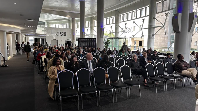 Speaker presenting at the Johannesburg Stock Exchange on Agentic OS and enterprise AI strategy in front of a large screen.