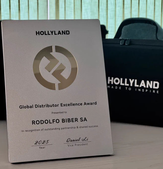Placa metálica del Global Distributor Excellence Award 2025 de Hollyland, entregada a Rodolfo Biber SA en reconocimiento a su destacada labor como distribuidor, junto a una bolsa de transporte de la marca con el lema "Made to Inspire".