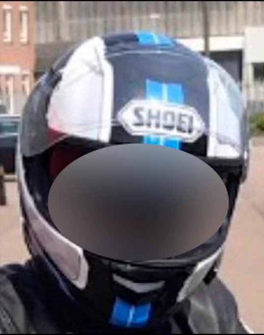 A Shoei motorcycle helmet with black, white, and blue detailing, worn by a rider.