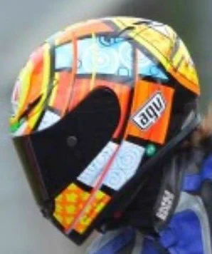 A colourful motorcycle helmet with an abstract, geometric design in orange, yellow, and black.