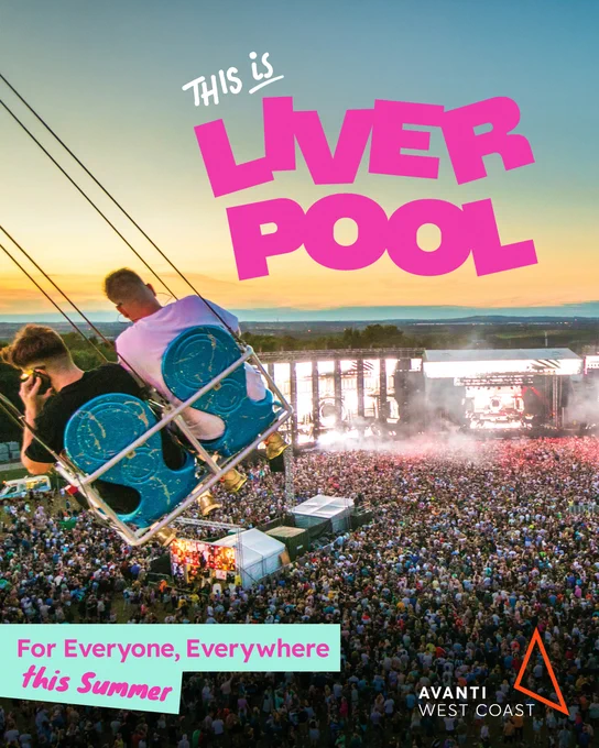 A music festival with a large stage and a crowd in front of it. There is two people on a swing going over the crowd. The text on it says 'This is Liverpool' in pink text.  