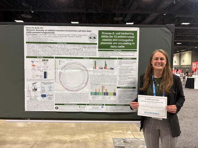Danielle Gregory stands next to her scientific poster holding her award certificate. She is smiling. 