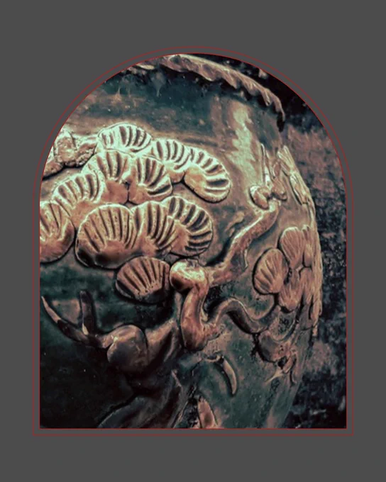 A closeup of a tarnished but shiny vase with sea scenes engraved on it