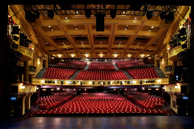 A photo showing a warmly lit interior of a large theatre 