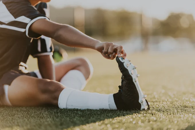Person doing stretches wearing cleats