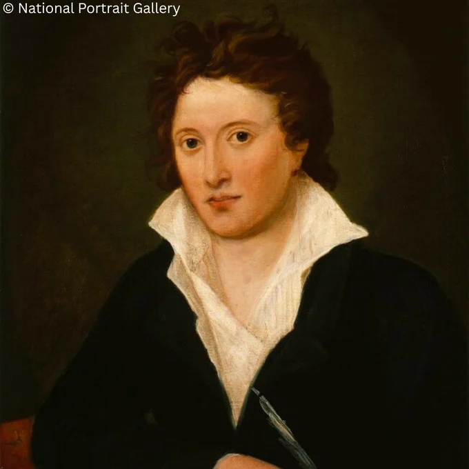Portrait of a person with short, curly dark hair, wearing a black coat over a white shirt with a high collar. They are gazing at the viewer with a slight smile, holding a quill pen in one hand, set against a dark background.