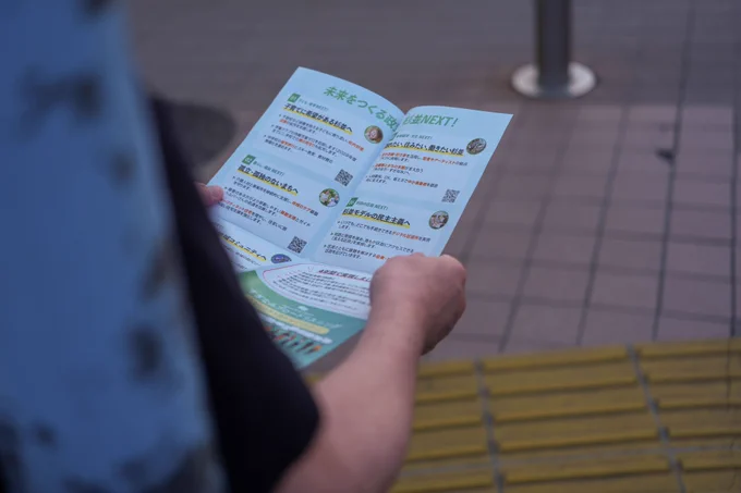 岸本さとこのチラシを読まれている方のお手元。