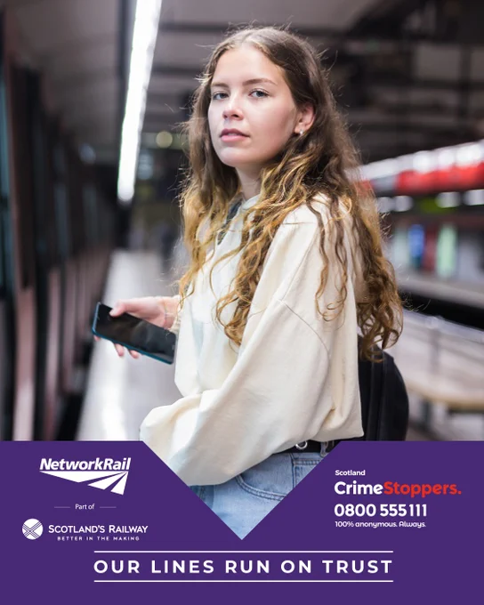 A person stands on a train platform holding a phone, with blurred train tracks in the background. 

The image includes logos for Network Rail and Scotland's Railway, along with a CrimeStoppers contact number. The text reads, "Our lines run on trust."