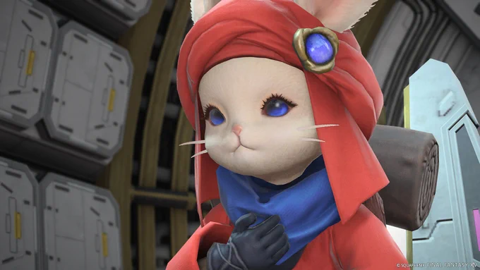 Une capture d'écran de Final Fantasy 14 qui montre un lapin humanoïde qui a un turban rouge sur la tête décoré d'un bijou bleu, une écharpe bleue ainsi qu'une tenue rouge en tissu. Il a la main sur son torse et se trouve dans une sorte de vaisseau spatial.
