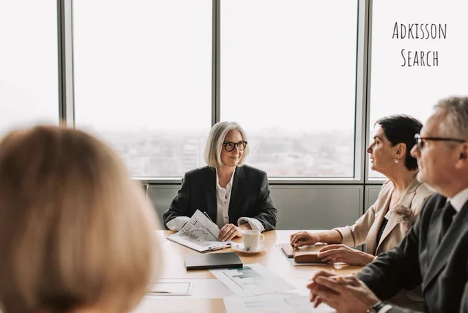 A group of professionals engaged in a business meeting inside a modern office boardroom.