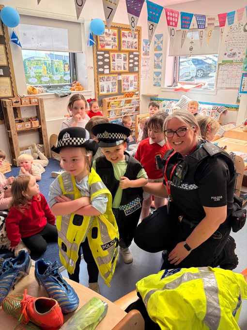 Children dressed as police officers with a real police officer in a classroom setting.