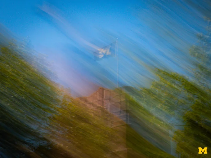 A motion blur photo of the Michigan Union and Block M flag.